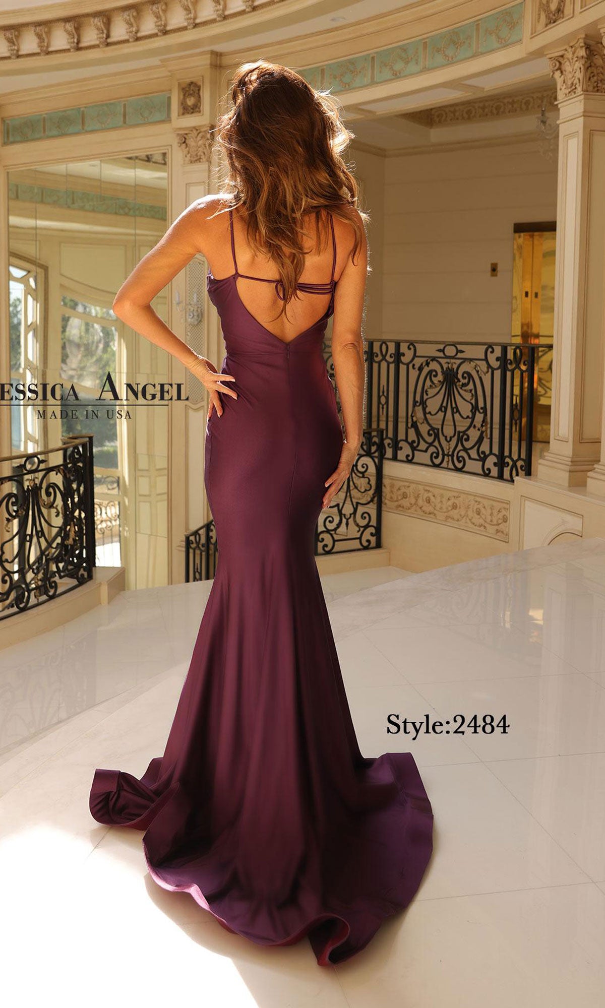 Woman wearing the Jessica Angel 2484 Cut-Out Long Prom Dress in purple, featuring a fitted silhouette, floor-length design, spaghetti straps, and low back, standing indoors in an elegant setting.